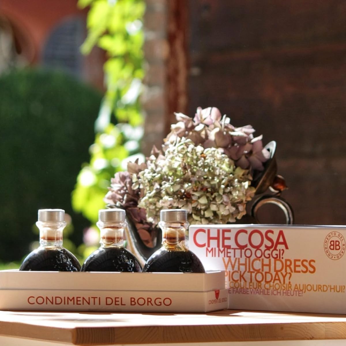 Three bottles of olive oil and a box labeled 'Checosa' on a wooden surface with a blurred background.