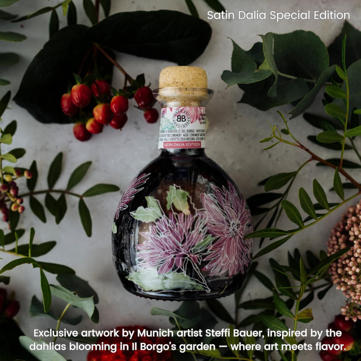 Bottle with floral design surrounded by greenery and berries, featuring Satin Dalia Special Edition branding.