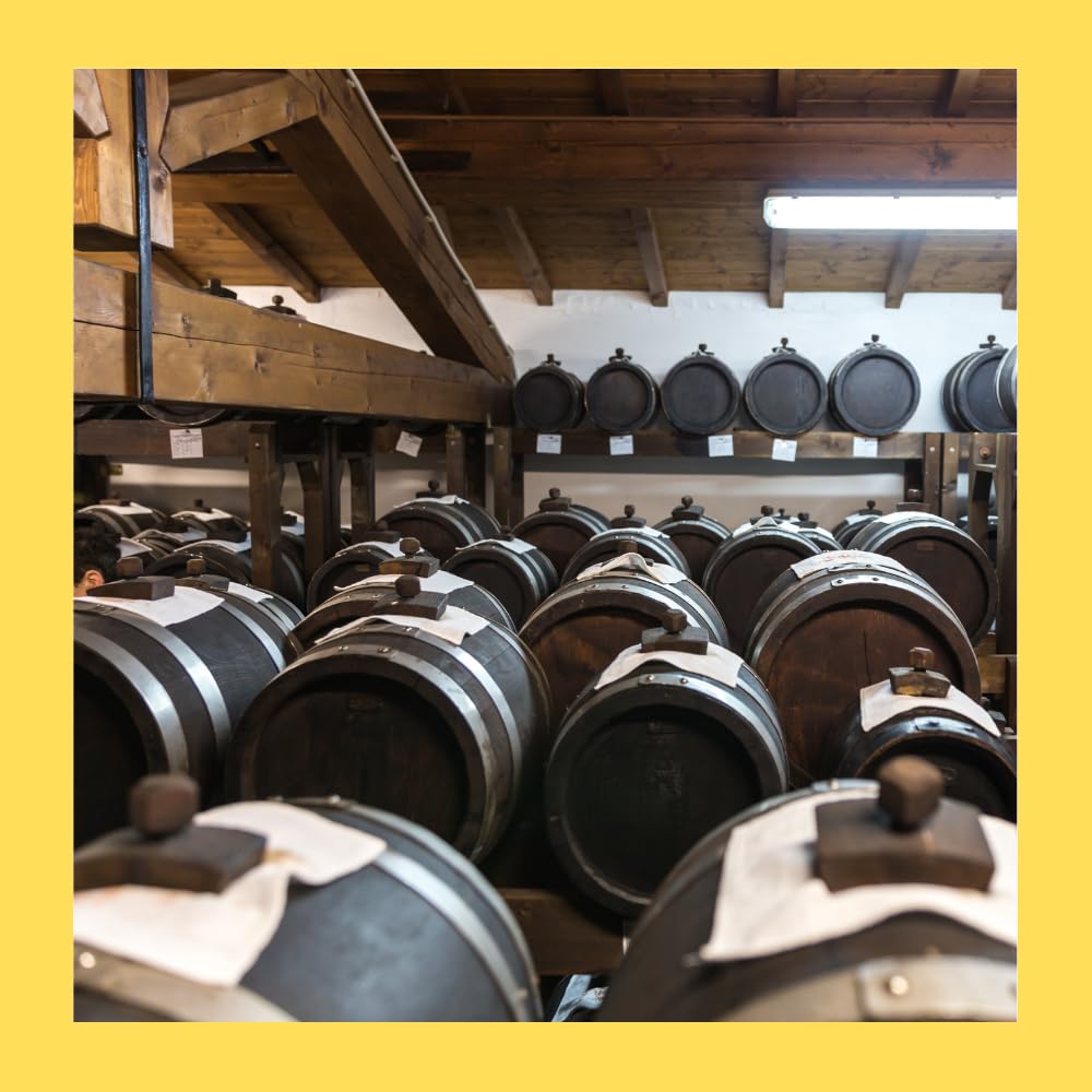 Wooden barrels arranged in a traditional vinegar aging cellar, used for producing authentic balsamic vinegar of Modena.