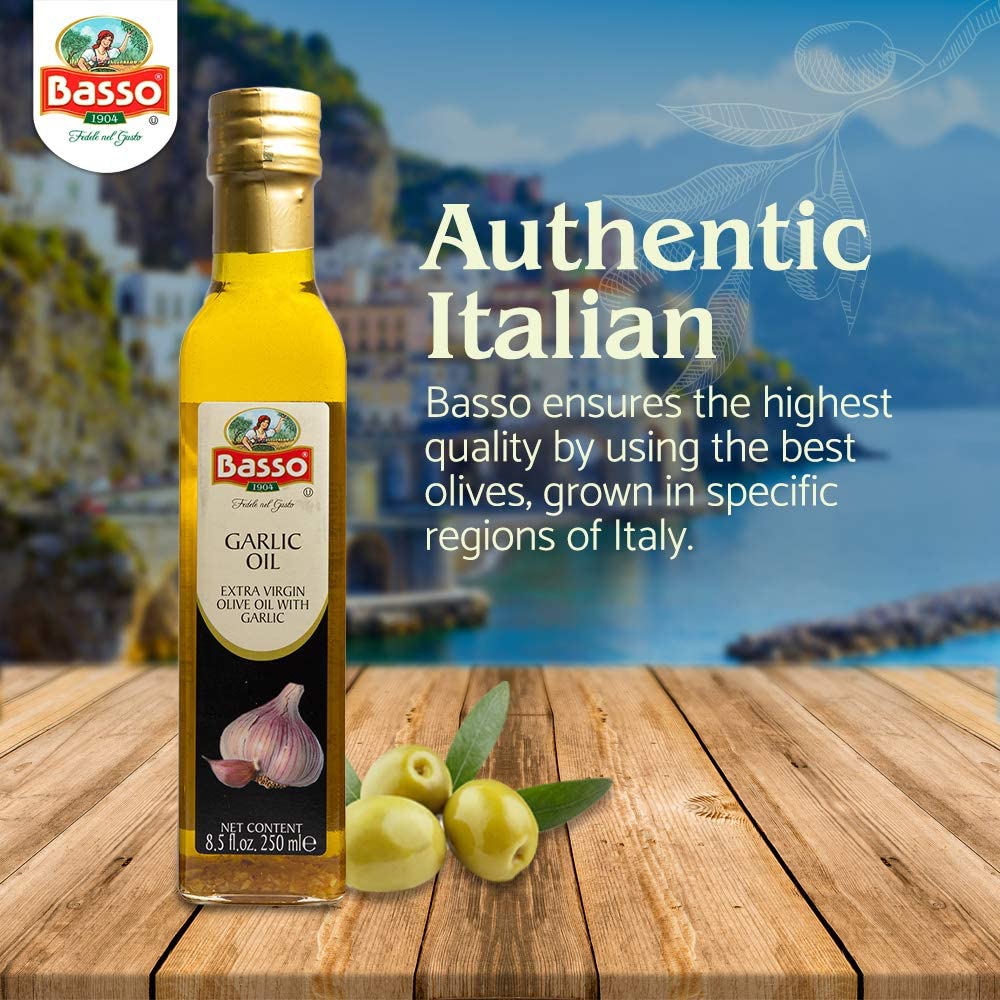 Basso 1904 Garlic Infused Extra Virgin Olive Oil 8.5 fl oz (250 ml) bottle on a wooden table with fresh olives, set against an Italian coastal backdrop, highlighting its authentic Italian origin and quality.