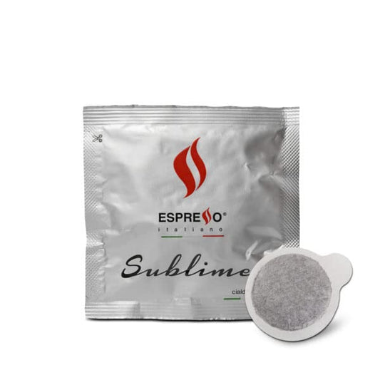 Box of Espresso Italiano Sublime E.S.E. Coffee Pods (100 count) with a fresh espresso served in a white cup and saucer, showcasing compostable pods and roasted coffee beans.