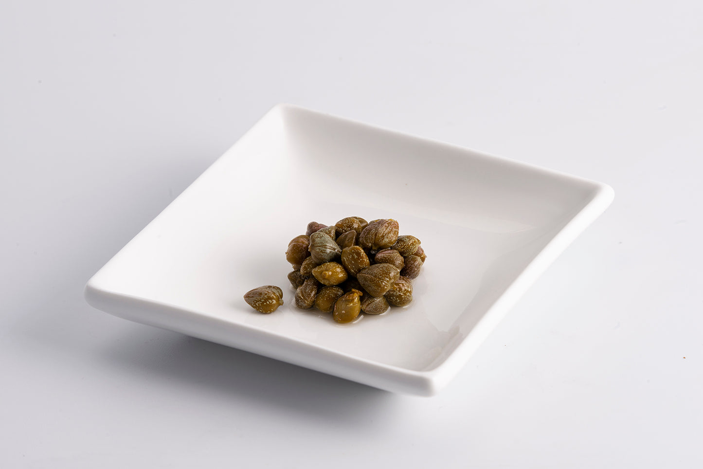 Close-up of Fratelli D’Amico Italian capers served on a white dish, showing their natural texture and vibrant flavor.