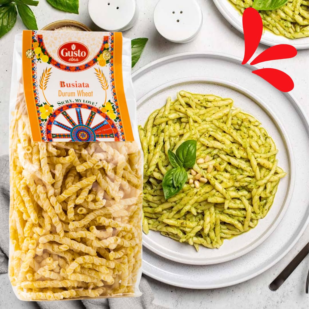 Bag of Gusto Etna Busiata pasta made from durum wheat, displayed next to a white plate of cooked busiata pasta tossed in fresh basil pesto and garnished with pine nuts,