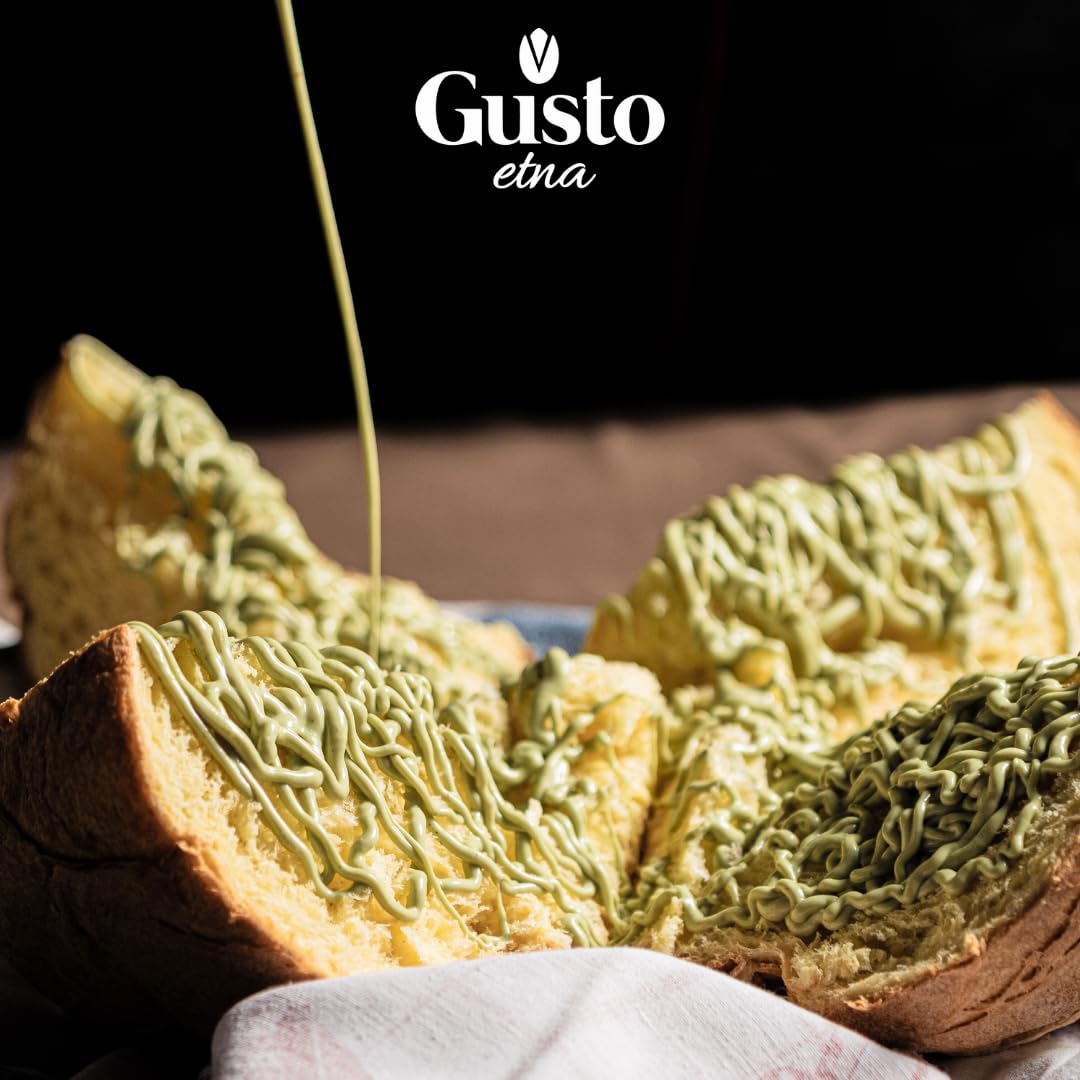 Artisan panettone sliced and topped with generous swirls of creamy pistachio butter, with extra pistachio butter being poured over the top, creating a decadent dessert presentation