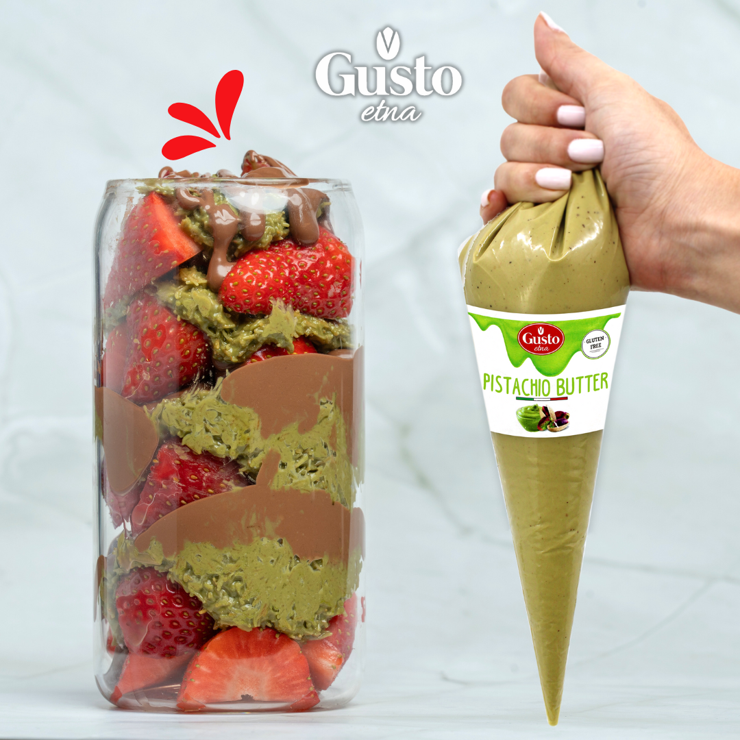 Dessert jar layered with fresh strawberries, pistachio cream, and chocolate, alongside Gusto Etna Pistachio Butter packaging.