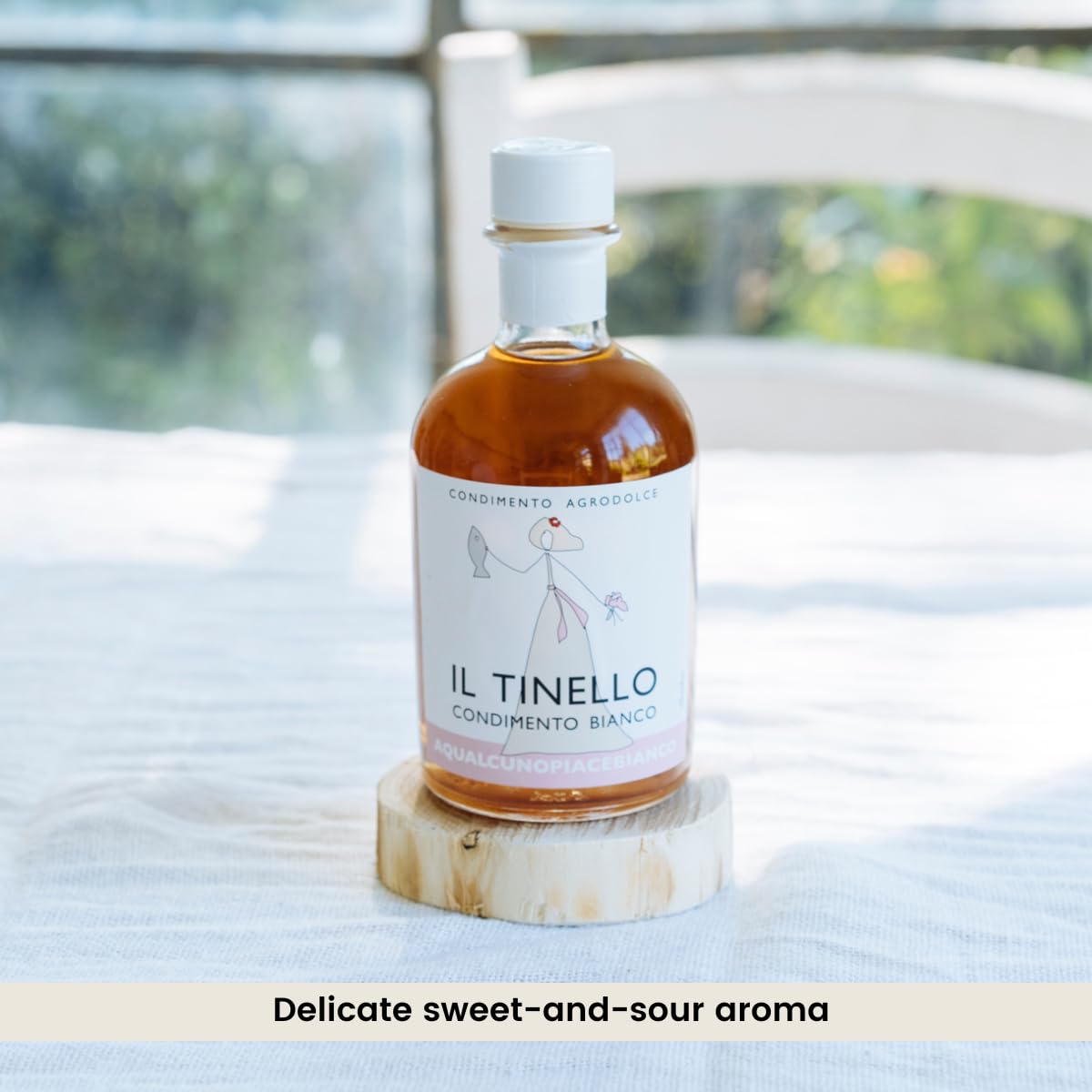 Bottle of Il Tinello on a wooden coaster with a blurred outdoor background