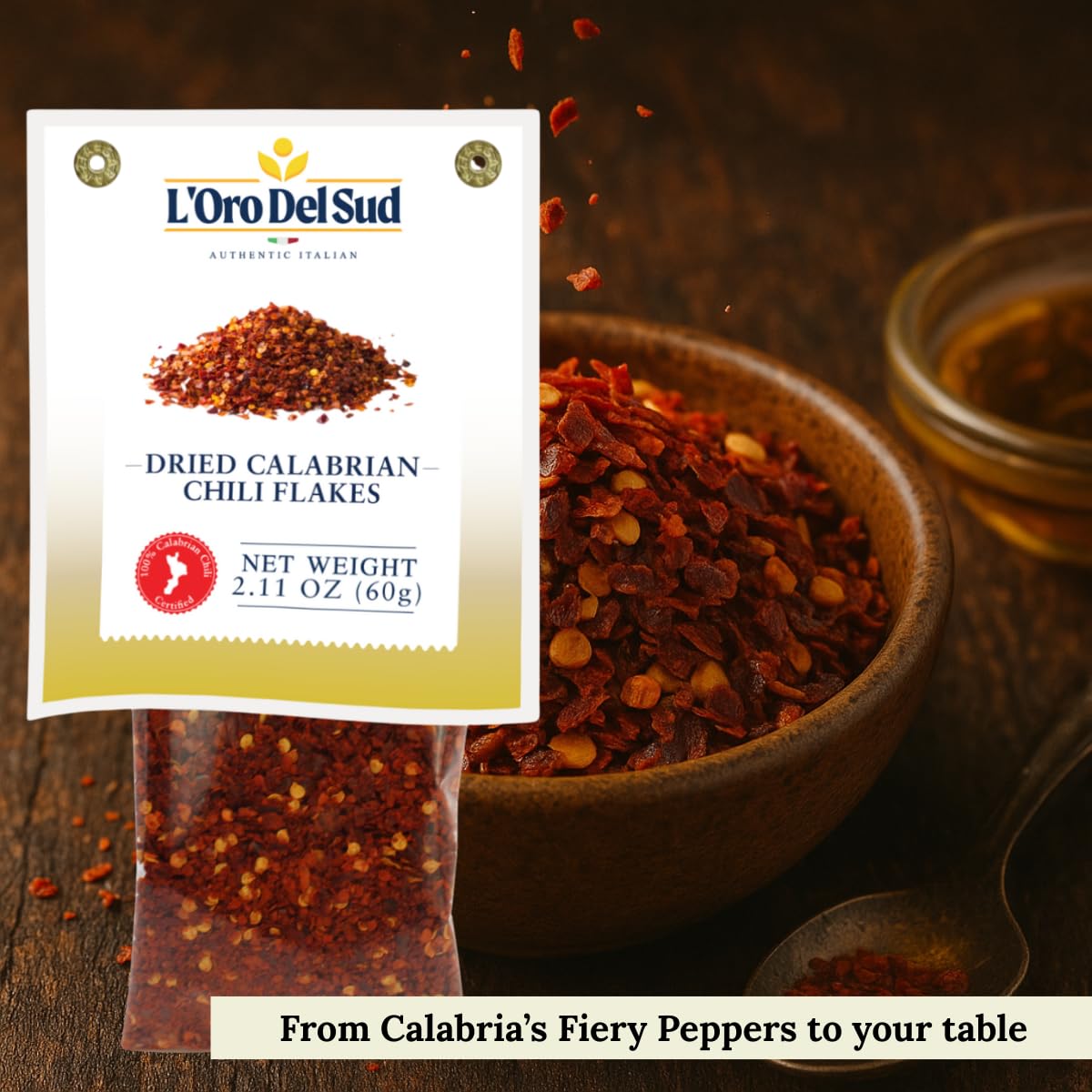 L'Oro Del Sud dried calabrian chili flakes packaging with chili flakes in a bowl on a wooden surface.