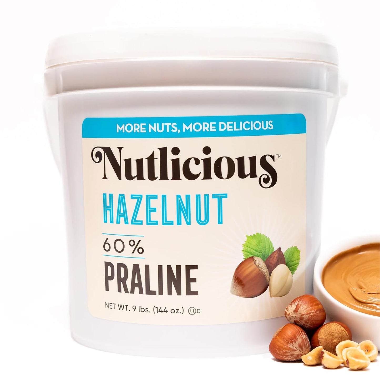 White tub of Nutlicious Hazelnut 60% Praline Spread with hazelnuts and a bowl of smooth hazelnut cream.