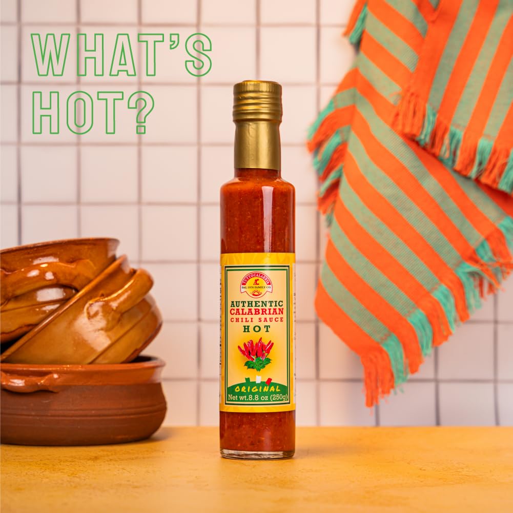 TuttoCalabria Hot sauce bottle with a colorful label on a wooden surface with a tiled wall background.