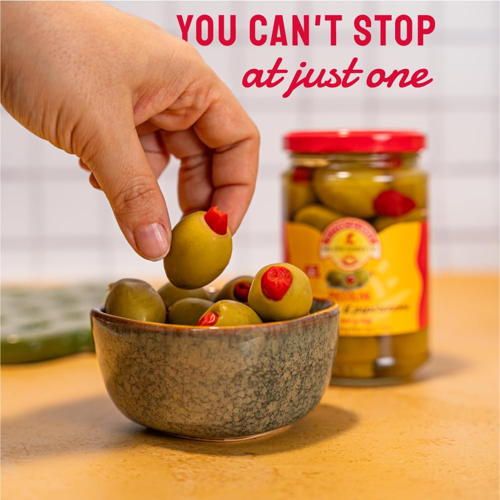 Hand picking olives from a bowl with a jar of olives in the background, text 'You can't stop at just one' displayed.