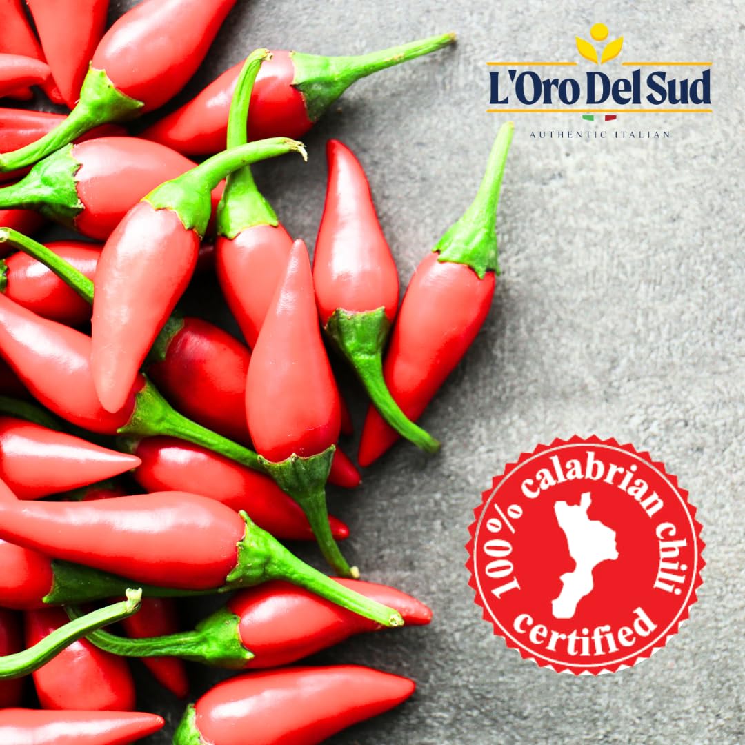 Red chili peppers with green stems on a gray surface, featuring L'Oro Del Sud branding.