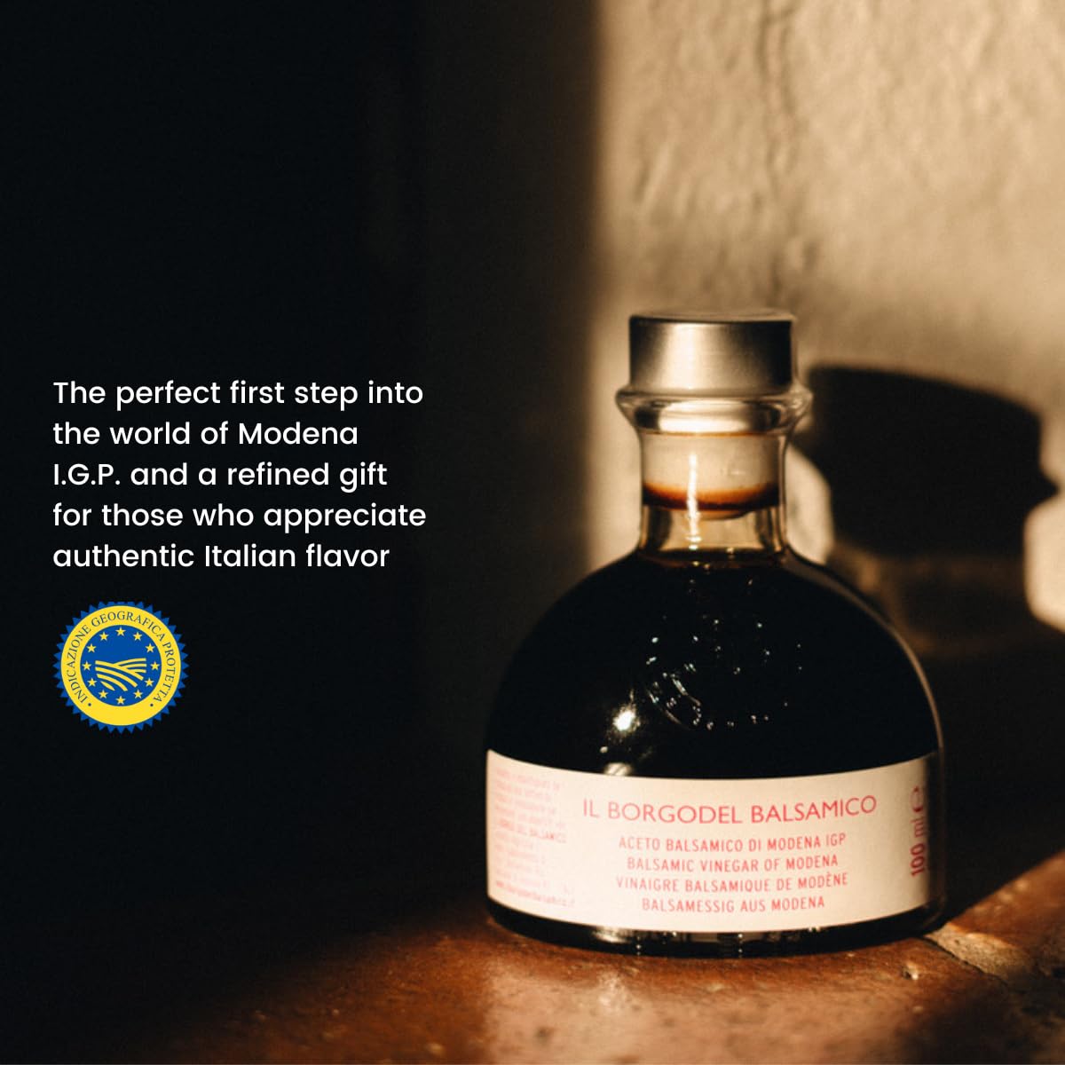 Bottle of Balsamic vinegar with a label and text about Modena I.G.P. on a wooden surface.