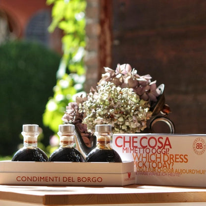 Three bottles of olive oil and a box labeled 'Checosa' on a wooden surface with a blurred background.