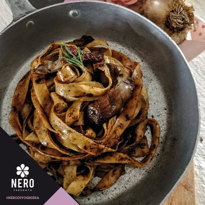 Pasta dish with meat in a gray pan, featuring the Nero brand logo.