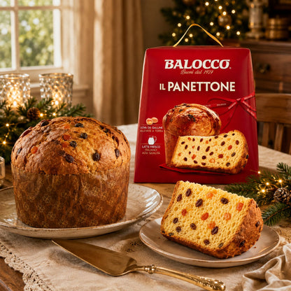 A loaf and sliced Panettone bread displayed on plates in a festive holiday kitchen setting, with the red Balocco Il Panettone box standing behind it.