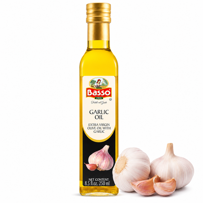 A bottle of Basso Garlic Oil next to three garlic bulbs and garlic cloves on a clean white background.