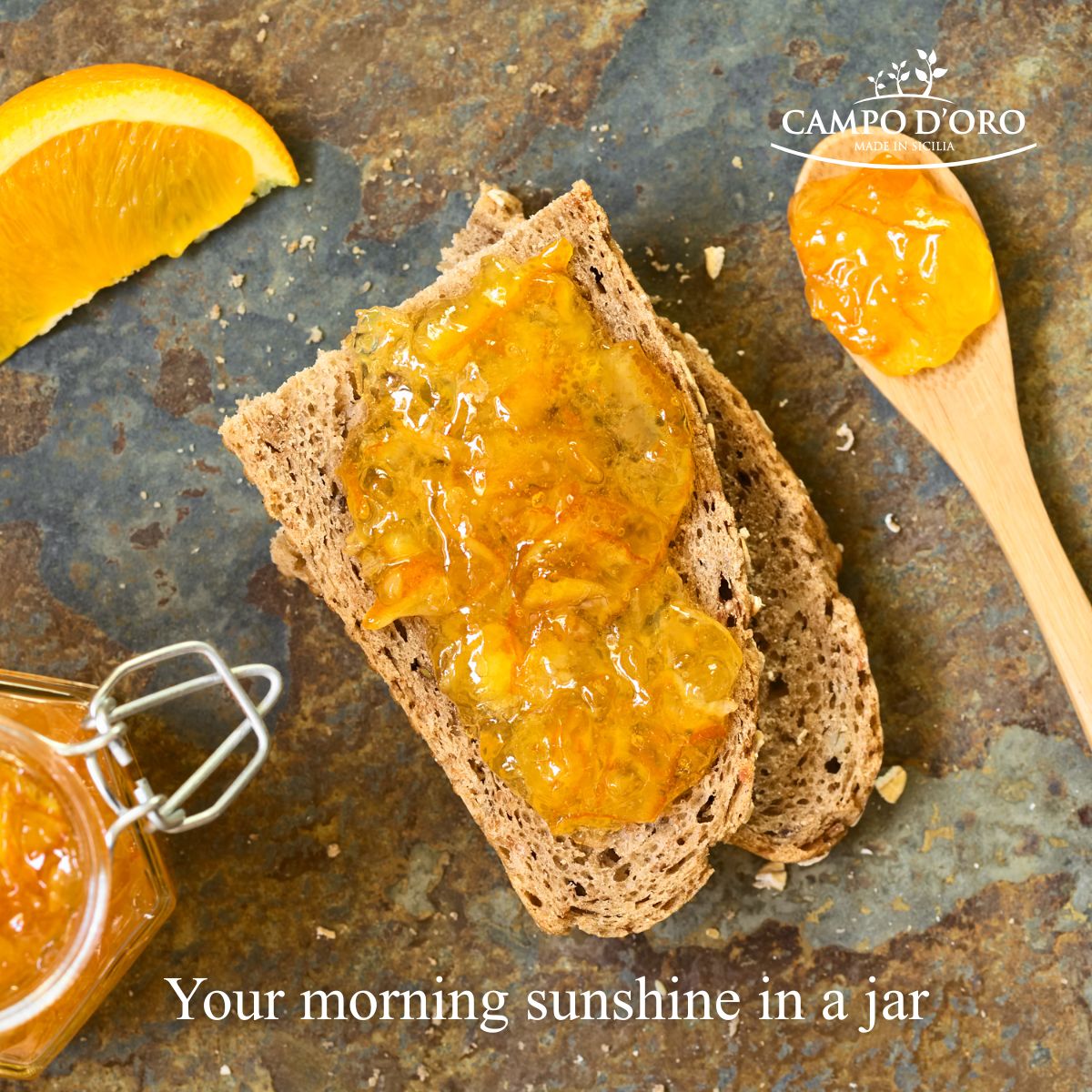 Toast with orange jam on a rustic surface, featuring Campo d'Oro branding.