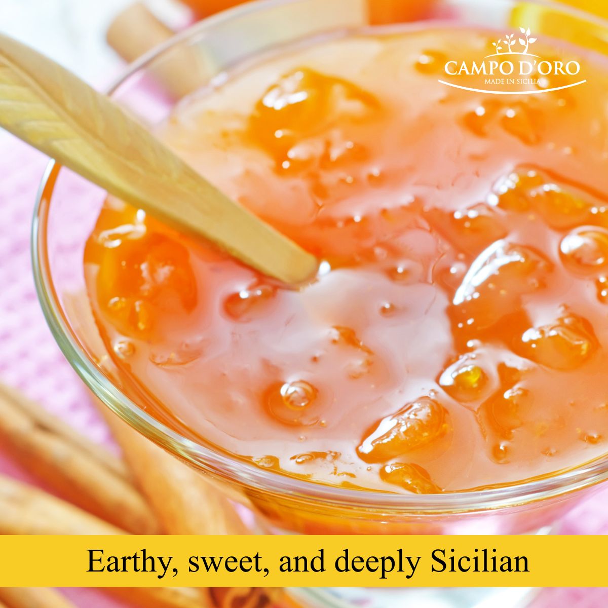 Glass bowl with apricot jam and a wooden spoon, with 'Campo D'Oro' branding.