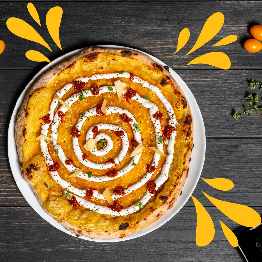 Neapolitan-style pizza topped with yellow Datterino tomato sauce, spirals of cream, chili flakes, and fresh herbs, served on a white plate over a dark wooden table with decorative yellow tomato graphics.