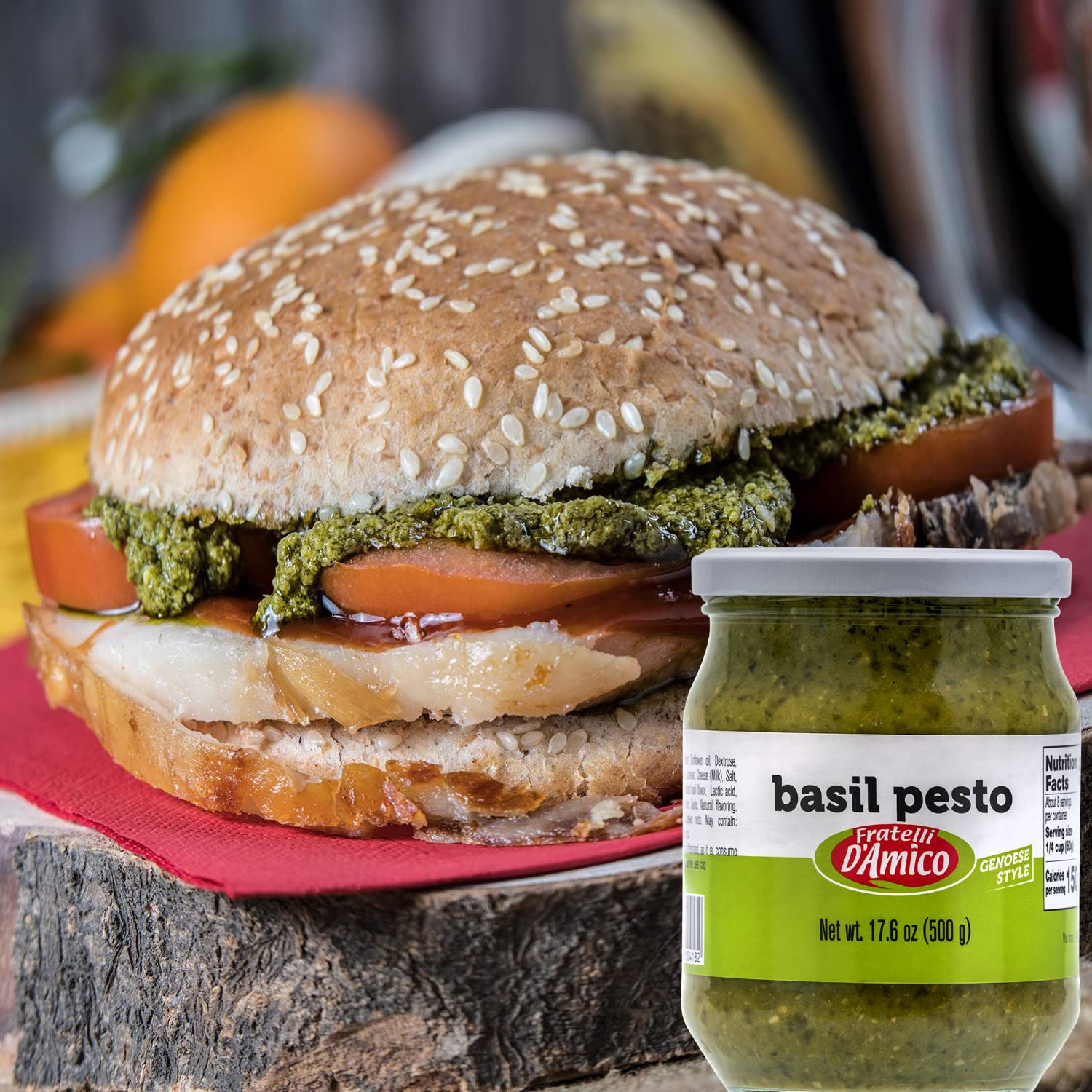 Close-up of a gourmet sandwich with tomato, chicken, and Fratelli D’Amico Basil Pesto, showcasing the jar of Italian Genoese-style pesto in the foreground.