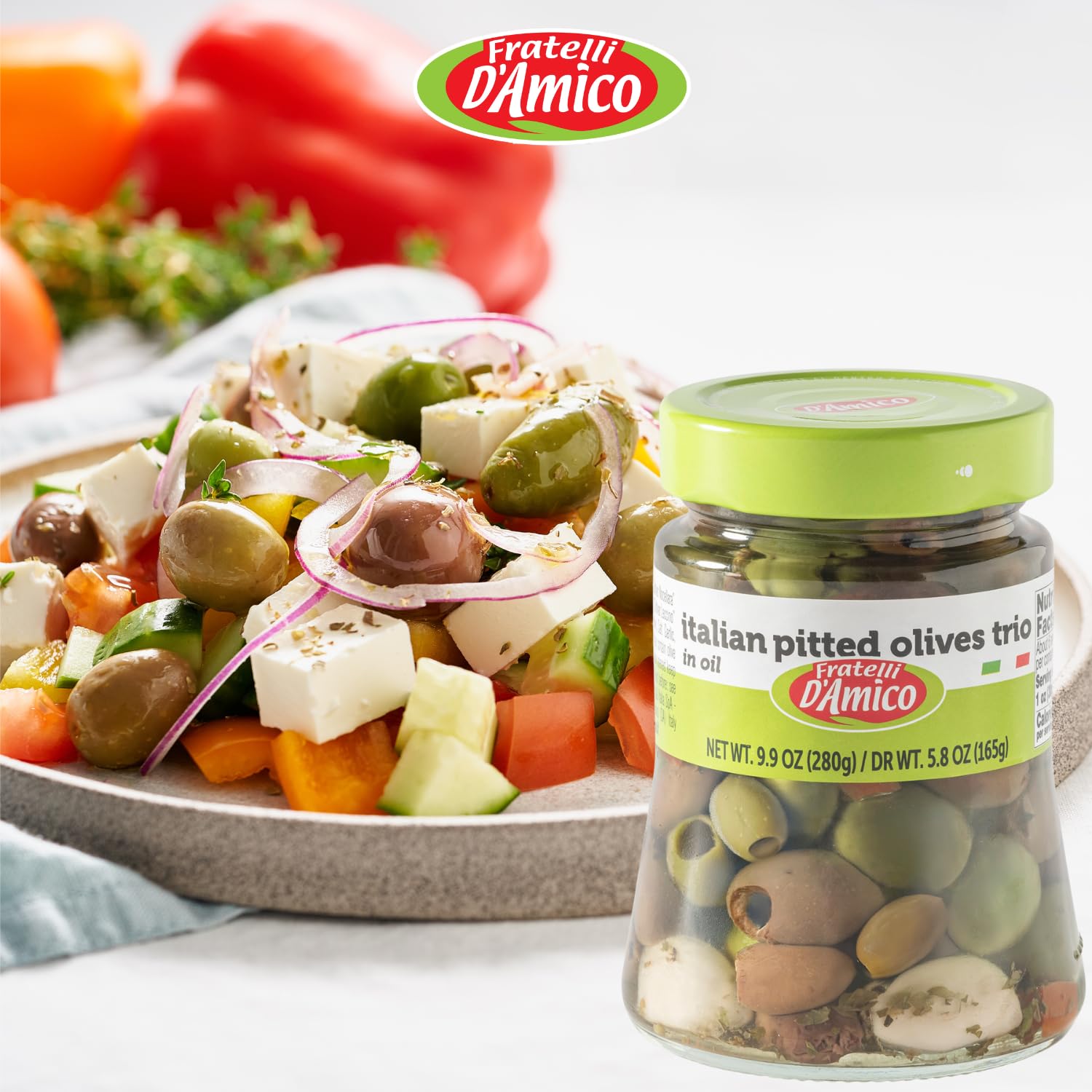 Fratelli D’Amico Italian Pitted Olives Trio jar with Mediterranean Greek salad of feta cheese, cucumbers, tomatoes, onions, and peppers, highlighting authentic Italian flavor.