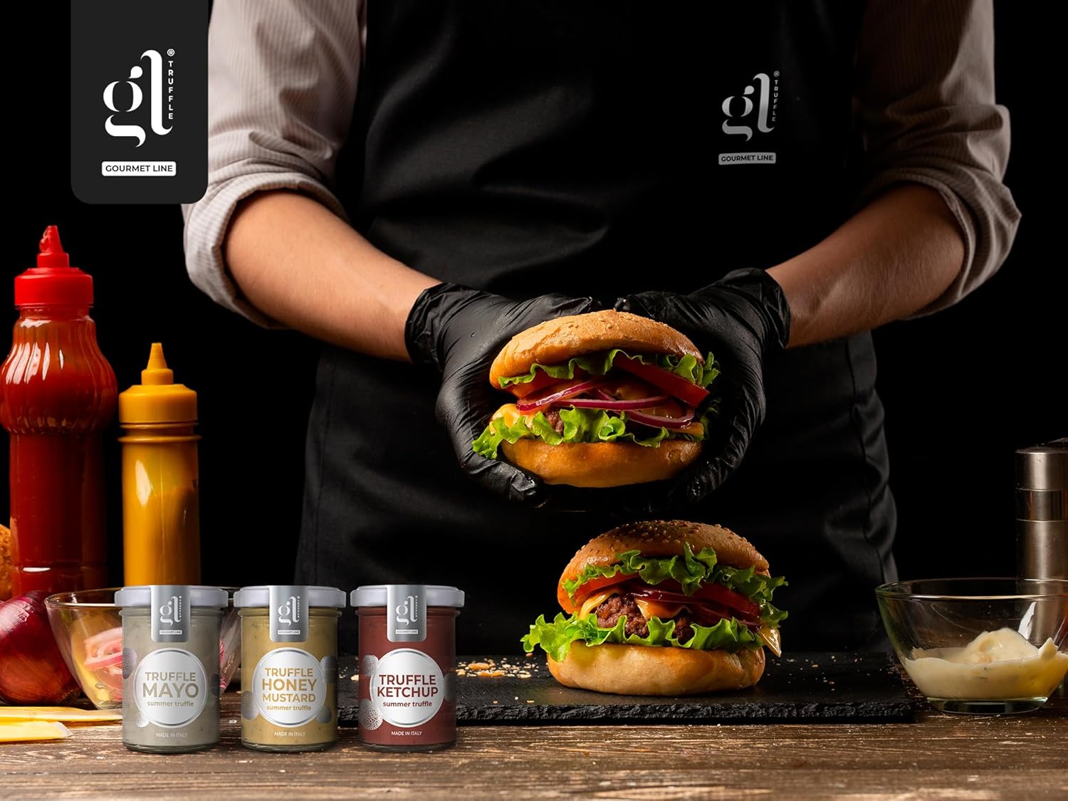 Chef preparing gourmet burgers with fresh lettuce, tomato, and onion, featuring GL Truffle condiments — Truffle Mayo, Truffle Honey Mustard, and Truffle Ketchup — displayed in front, premium truffle sauces made in Italy