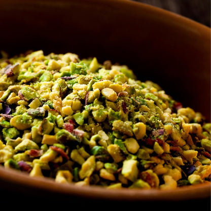 Close-up of premium chopped pistachios in a wooden bowl, showcasing vibrant green and purple hues, ideal for baking, desserts, and gourmet toppings.