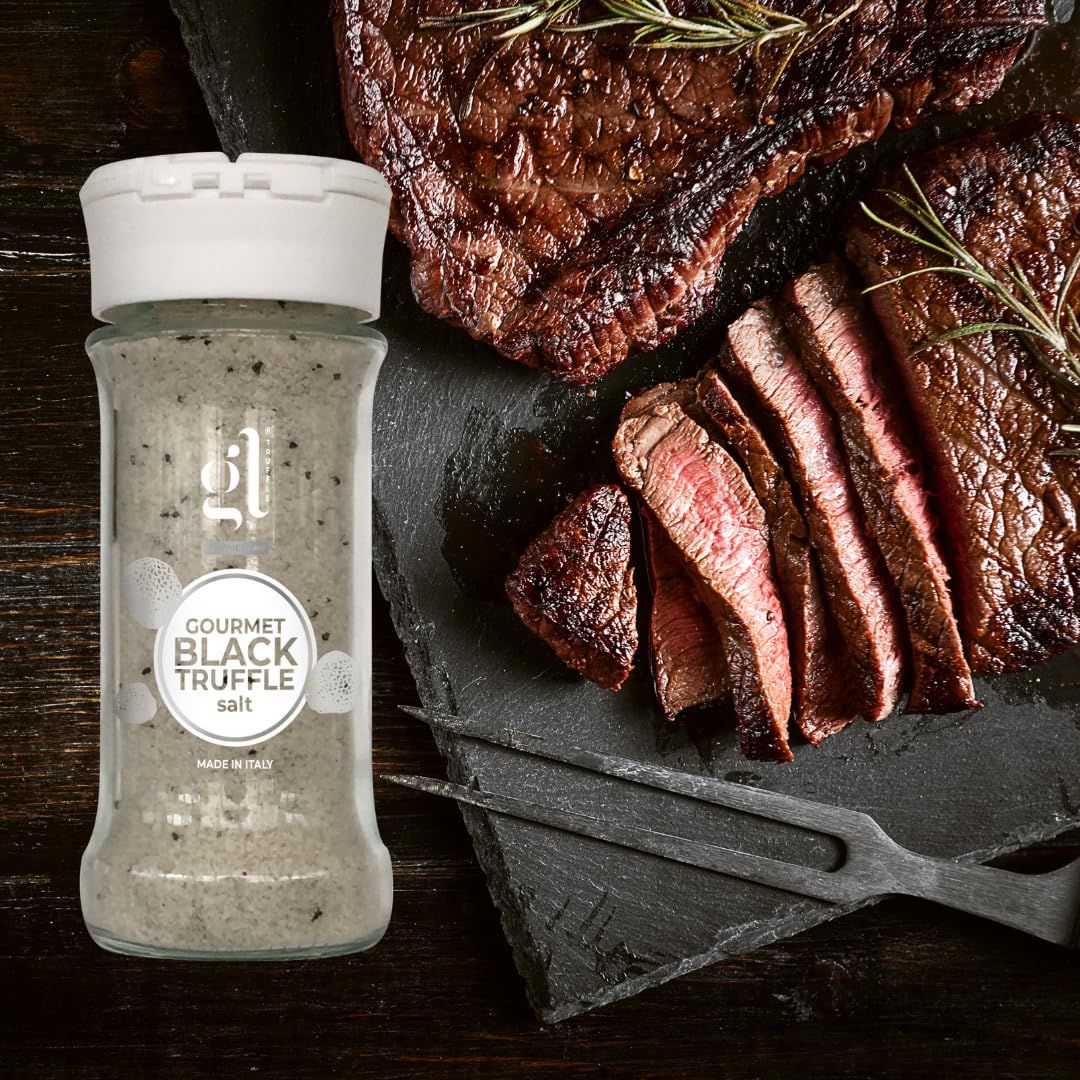 Bottle of Gourmet Black Truffle Salt next to sliced steak on a wooden surface