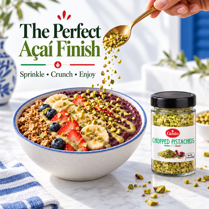 A jar of Caisto Chopped Pistachios shown next to a styled açaí bowl with banana, berries, granola, and drizzles, with a hand sprinkling more pistachios. Promotional text reads 'The Perfect Acai Finish'.