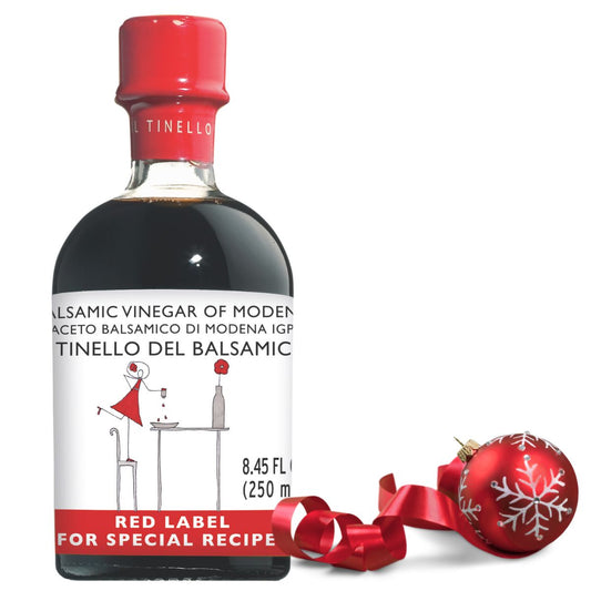 Balsamic vinegar bottle with red label and decorative ornament on a white background