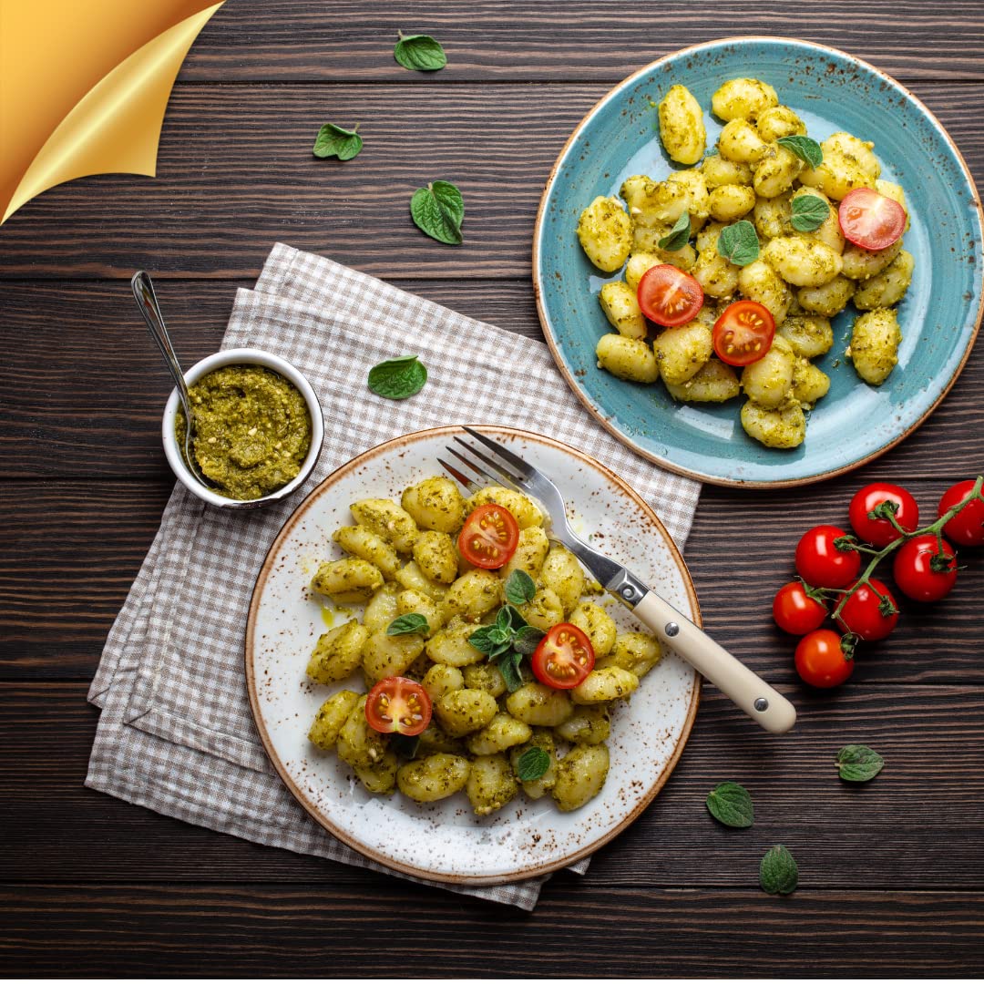 Plate of Italian potato gnocchi with pesto sauce, cherry tomatoes, and fresh herbs, authentic L’Oro Del Sud pasta dish