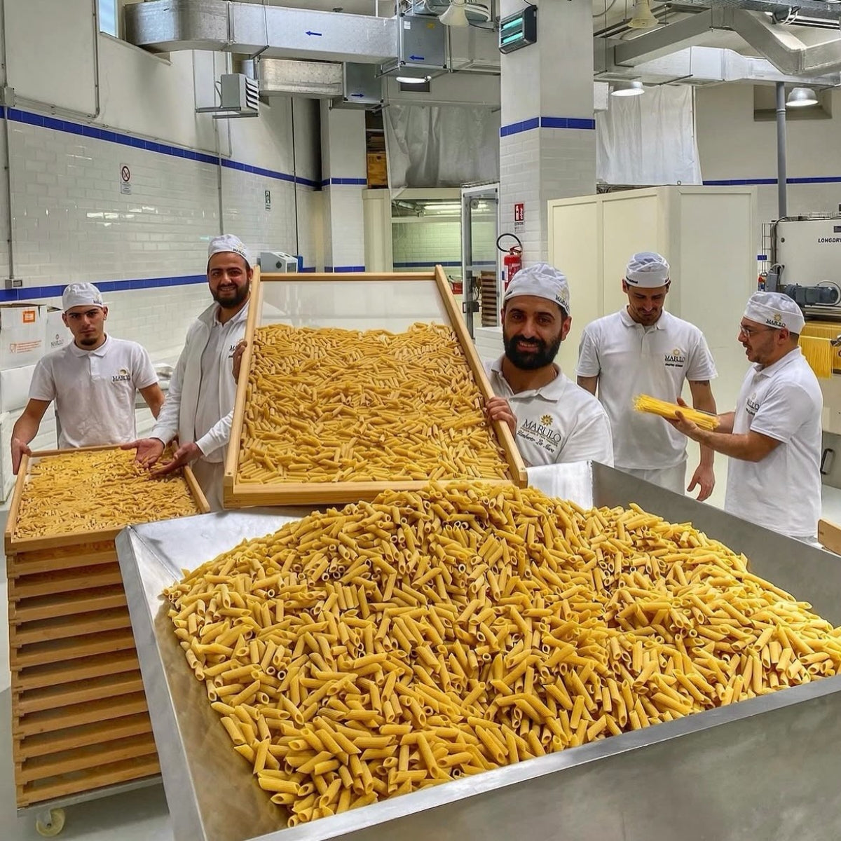 Marulo pasta makers beside trays of artisan pasta inside the production facility