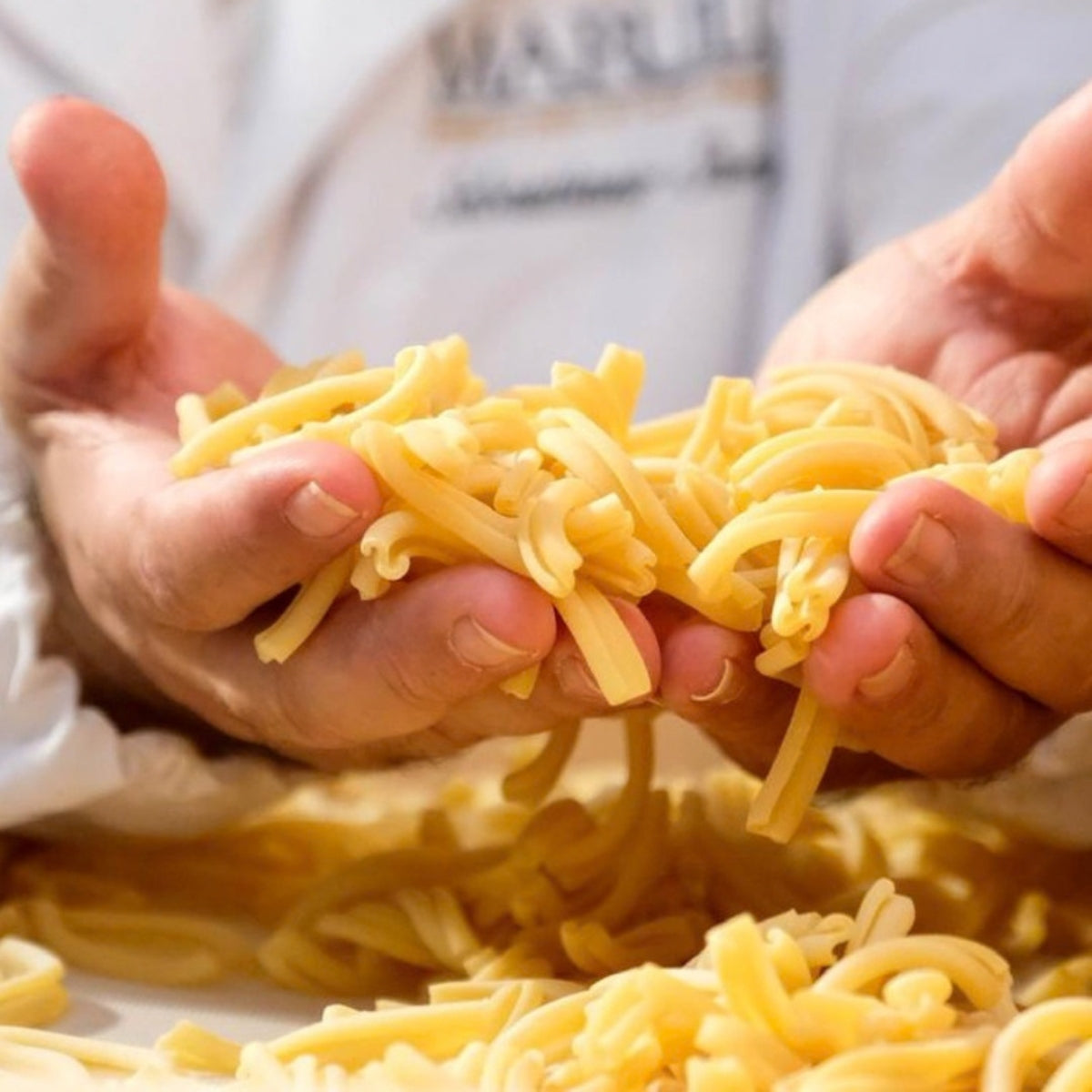 Hands holding freshly crafted Marulo pasta during artisan production