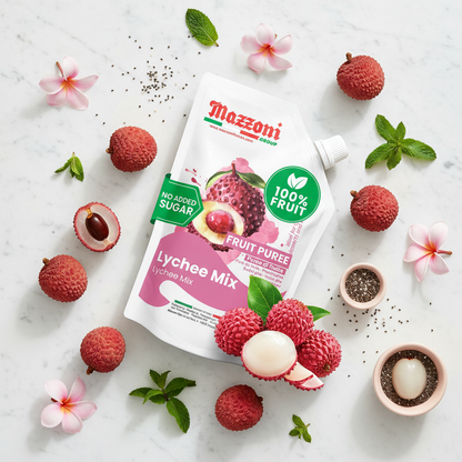MAZZONI LYCHEE MIX FRUIT PUREE POUCH SURROUNDED BY FRESH LYCHEES, FLOWERS, MINT LEAVES, AND SEEDS ON A LIGHT BACKGROUND