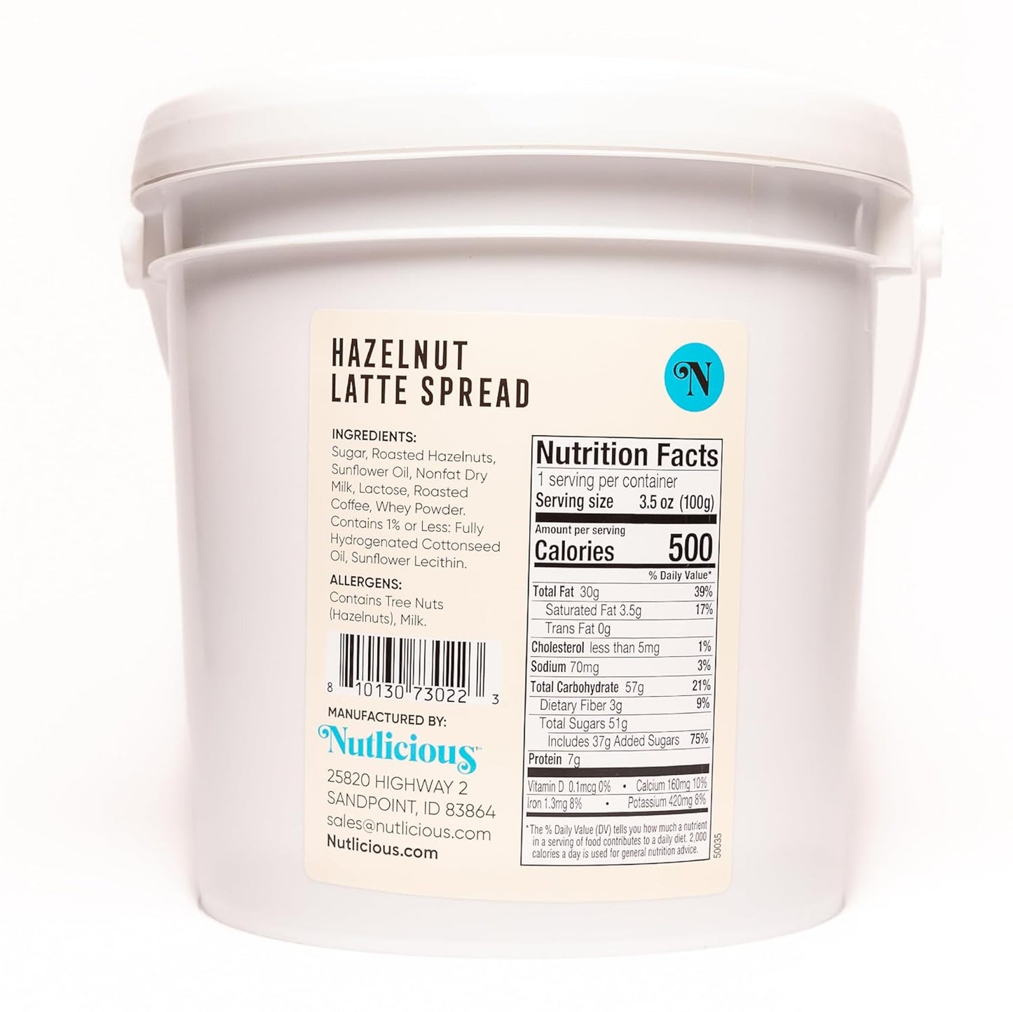 Back view of Nutlicious Hazelnut Latte Spread 9 lb tub showing nutrition facts, ingredient list (sugar, roasted hazelnuts, sunflower oil, nonfat dry milk, lactose, roasted coffee, whey powder), allergen information, barcode, and manufacturer details.