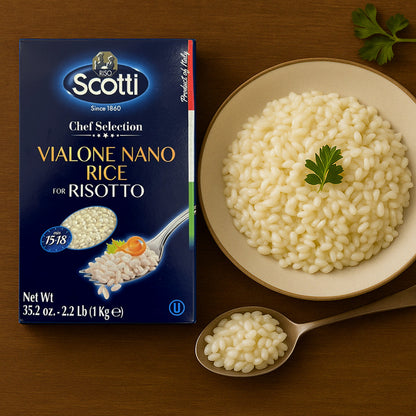 A box of Riso Scotti Vialone Nano Rice for Risotto (2.2 lb / 1 kg) is displayed on a wooden surface next to a bowl filled with cooked Vialone Nano rice garnished with parsley. A spoon with cooked rice rests in front of the bowl.