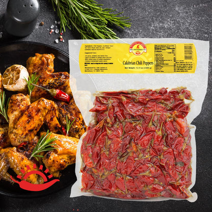 Packaged Calabrian chili peppers with a dish of roasted chicken and herbs on a dark surface.