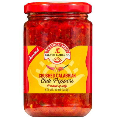 Jar of crushed calabrian chili peppers with a red lid on a white background