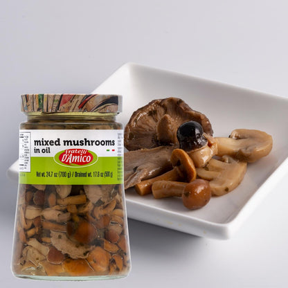 Fratelli D’Amico Mixed Mushrooms in Oil jar, 24.7 oz (700 g) / drained 17.6 oz (500 g), displayed next to a white dish with assorted marinated mushrooms including porcini, oyster, and shimeji
